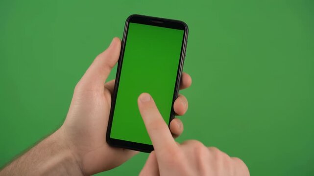 Hand holding green screen smartphone during digital interaction against a chroma key background