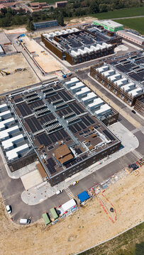 Aerial view of the Stack Infrastructure MIL04 Campus featuring data center buildings with solar panels on rooftops, paved access roads, and construction areas in Vellezzo Bellini, Lombardy, Italy.