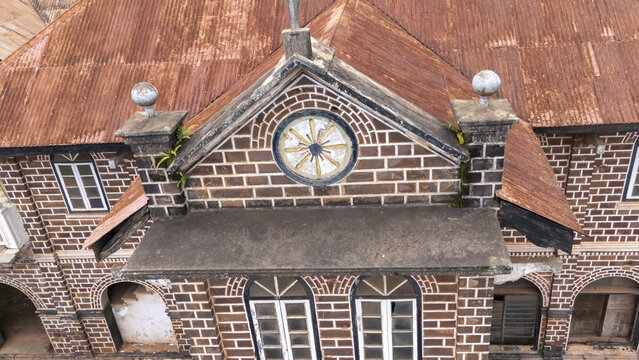 Aerial view of a historic brick building with a circular window and a weathered corrugated metal roof in Ngwo, Enugu, Nigeria.