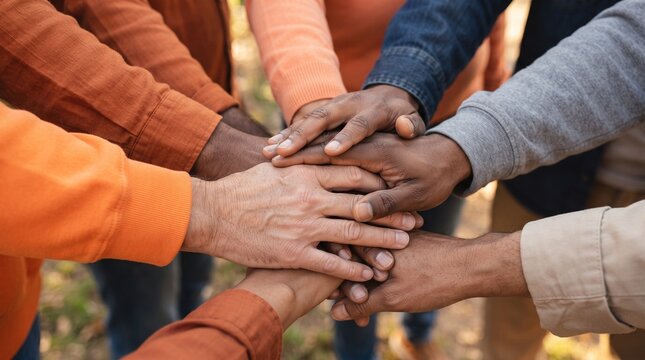 Multiethnic team putting hands together in a huddle, representing cooperation, diversity, and collective strength for a common goal