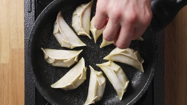 Chef shows crisp golden bottom of fried gyoza. Gyoza cooks with oil and steam for crunchy base and tender wrapper. Serve hot gyoza as Japanese street food with soy dip, chilli oil, sesame or scallion.