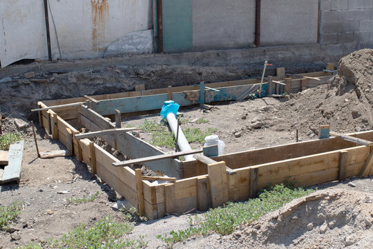 Wooden formwork prepared for pouring a concrete foundation at a residential construction site, showing an early stage of building work.
