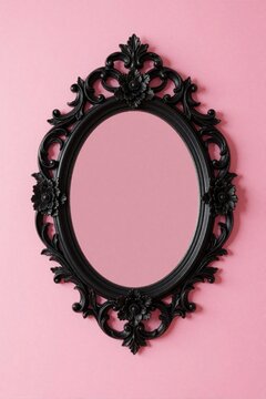 Ornate black oval mirror with floral details hangs on plain pink wall. Its decorative frame adds vintage charm, perfect for home interior design or beauty product ads.