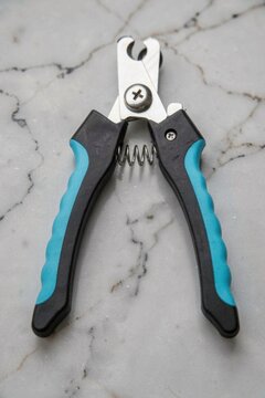 Blue and black pet nail clippers on a marble background
