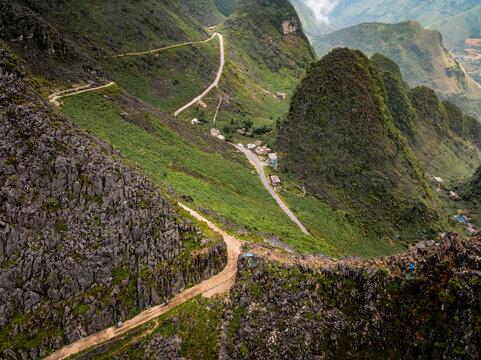 Aerial view of the winding mountain road through the dramatic karst landscape of Ha Giang with steep rocky cliffs and lush green valleys in Tien Du, Bac Ninh, Vietnam.
