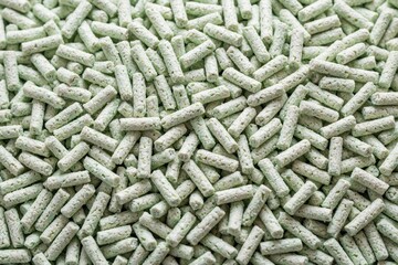 Fototapeta premium Close-up of light green tofu cat trash pellets filling the frame. These eco friendly pellets are made from soybeans forming small cylinders.