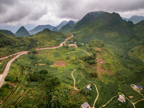 Aerial view of winding roads and lush green terraced fields nestled among the dramatic mountains of Ha Giang in Tien Du, Bac Ninh, Vietnam.
