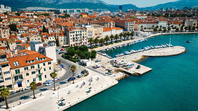 Aerial view of the historic harbor and waterfront of Split with boats docked along the pier, surrounded by stone buildings and the Adriatic Sea in Split, Split-Dalmatia County, Croatia.