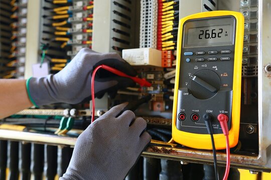 Electrician using a multimeter to test electrical panel wiring with electrician multimeter electrical