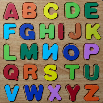 Colorful wooden English alphabet puzzle toy. Children educational wooden alphabet board puzzle with multicolored letters from A to Z arranged in rows for preschool learning and development