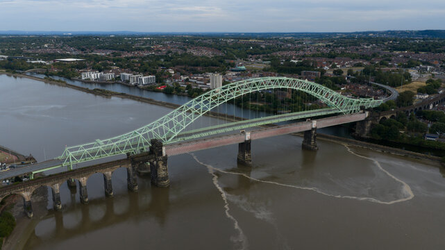 Aerial view of the Silver Jubilee Bridge spanning the River Mersey, featuring its green steel arch and adjacent railway viaduct, Runcorn, United Kingdom.