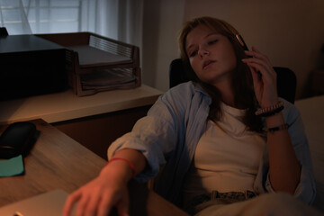 Fototapeta premium Tired teenage girl thinking while working late at night, feeling overwhelmed by homework and school projects, reflecting on academic pressure and procrastination