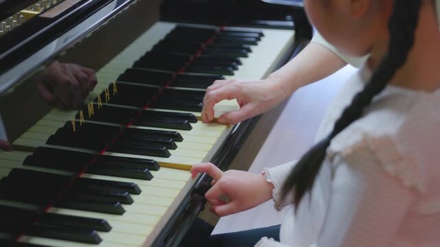 女性とピアノの鍵盤を指さして音を確認する女の子