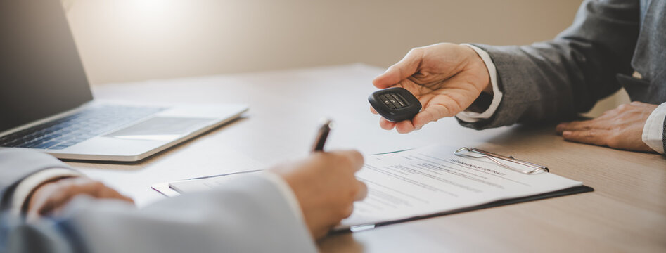 close up shots hands of client signing car lease form.