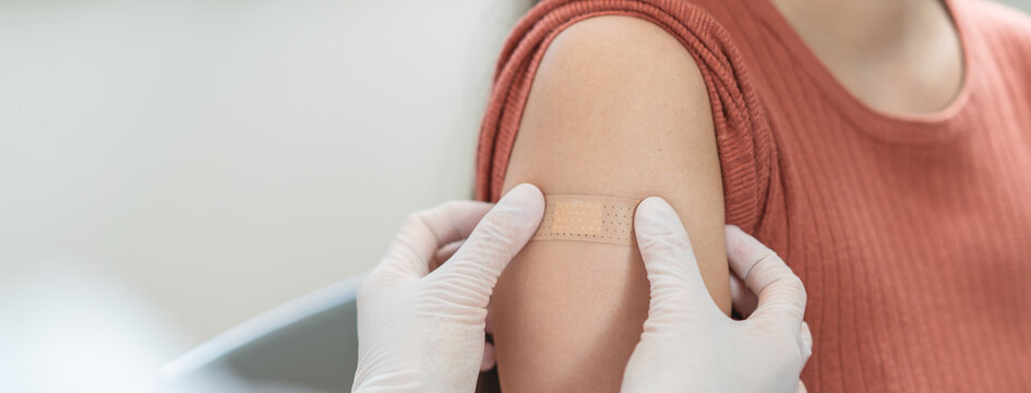 Close up of doctor applying adhesive bandage on girl arm after vaccination.