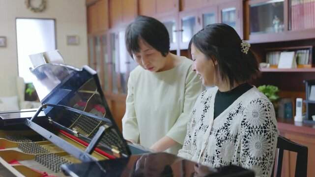 シニア女性の先生とピアノ教室で楽譜を確認する大人の女性