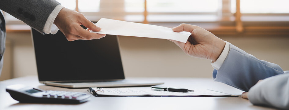 Close up of employee handing resignation letter or application to manager.