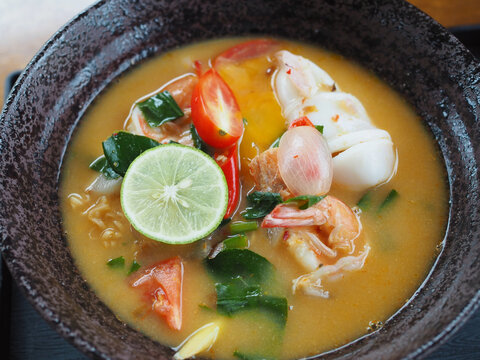 The tom yum instant noodles in the bowl contain shrimp and squid. It looks delicious and appetizing.