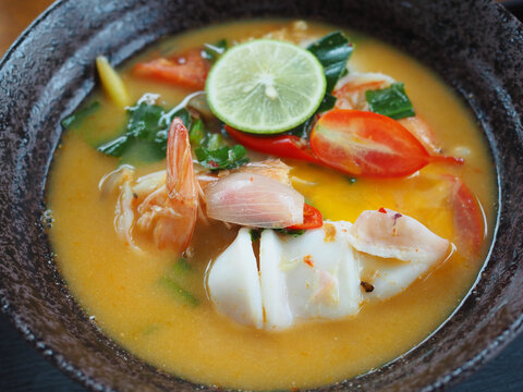The tom yum instant noodles in the bowl contain shrimp and squid. It looks delicious and appetizing.