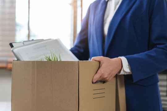 Close-up of a businessman holding a cardboard box with personal belongings after resignation.