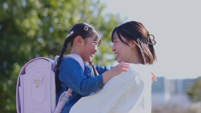 ランドセルの女の子を抱き上げて笑う母親