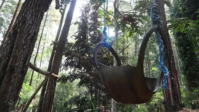 A handmade tire swing hanging from a tree in a lush forest. perfect for concepts of childhood nostalgia, relaxation, freedom, and peaceful leisure.