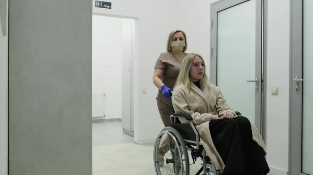 Nurse escorts woman through hallway for upcoming procedures. Doctor transports patient toward laboratory office for blood analyses. Slow motion