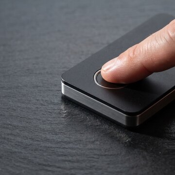 Biometric fingerprint scanner on black slate, person using finger touch sensor for secure access, modern identity verification technology