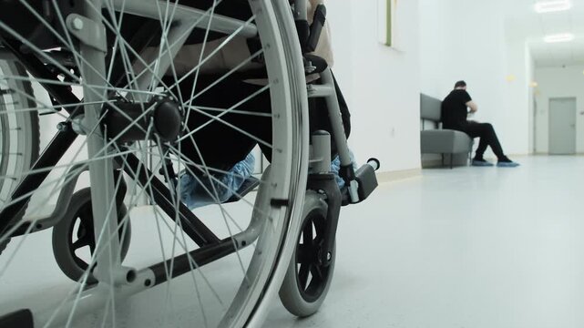 Disabled patient transported in wheelchair at healthcare facility closeup. Improving accessibility and mobility assistance in clinic
