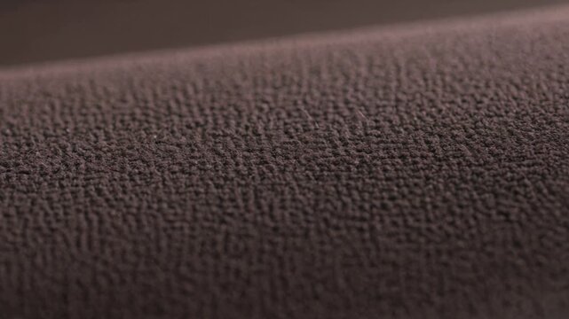 Close-up of a brown microfiber fabric texture, showcasing the detailed weave of the synthetic textile material used for upholstery, furniture, clothing, and home decor