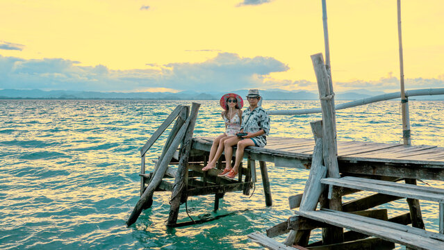 Couple tourist in happiness and relax moment on wooden pier, enjoy the summer trip in tropical island