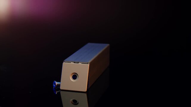 Metallic blue and copper block rotating on reflective black surface