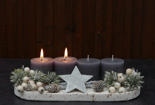 Second Sunday of Advent: Advent arrangement with berries, twigs, and two lit candles against a wooden background, with space for text.