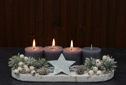 Third Sunday of Advent: Advent arrangement with berries, twigs, and three lit candles against a wooden background, with space for text.