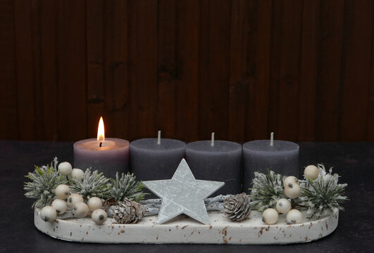 First Sunday of Advent: Advent arrangement with berries, twigs, and a lit candle against a wooden background, with space for text.