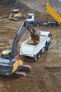 Excavator loading dirt into tipper truck at construction site