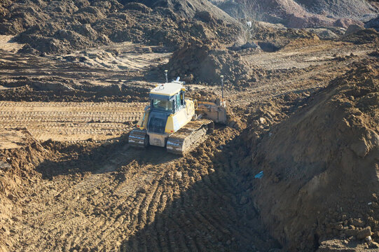 Yellow bulldozer working on earthworks at large construction site
