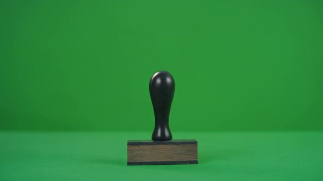 Hand stamping approval with a wooden seal on a green screen background during a business process