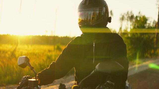 Motorcyclist riding through golden sunset countryside on a powerful street bike, capturing warm evening light, motion, and reflective helmet visor details