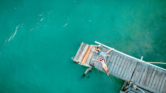 Top aerial view of couple tourist in happiness and relax moment on wooden pier, enjoy the summer trip in tropical island