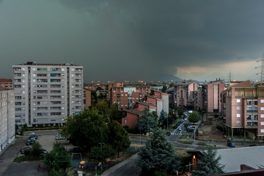 Area residenziale con palazzi, strade e alberi sotto un cielo scuro e tempestoso. Ideale per temi meteo, citt&agrave;, atmosfera drammatica, paesaggio urbano, cambiamento climatico e fotografia ambientale.