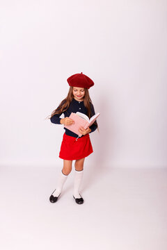 ull length portrait of happy little girl in red beret holding open notebook on white background