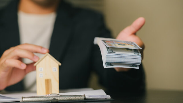 Businessman Holding Mortgage Documents with House Model and Credit Cards, Home loans or mortgages; loan approval; financial products.