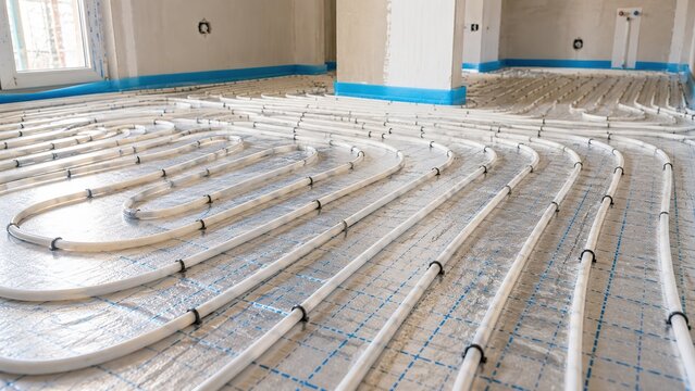 Underfloor heating pipes installed across an insulated floor in a new residential building, showing radiant heating, plumbing, construction and energy efficient home technology.
