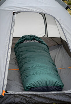 Green sleeping bag inside a gray camping tent, outdoor adventure and wilderness travel equipment, this essential equipment provides comfort and shelter for recreation and leisure activities