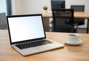 Fototapeta premium Laptop with blank white screen and coffee cup on a wooden desk in a modern office environment, the modern office environment features blurred chairs and tables in the background