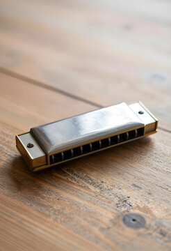 Silver and gold harmonica on a rustic wooden table, musical instrument for blues and folk music