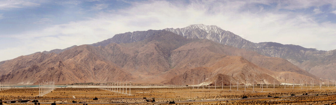 Aerial view of the San Gorgonio Pass wind farm with rows of wind turbines stretching across the desert landscape beneath the San Jacinto Mountains in Palm Springs, California, USA.