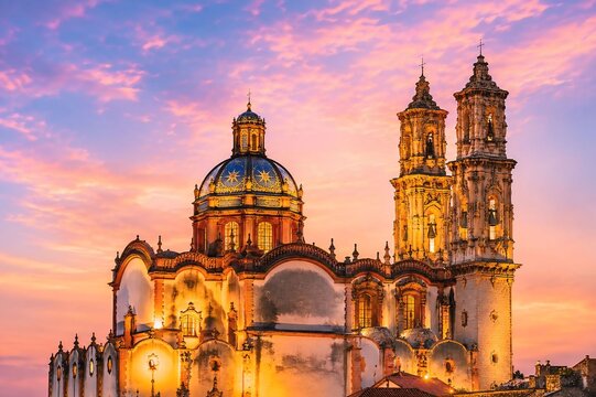 Ornate baroque santa prisca temple in taxco mexico during a pink and orange sunset sky with architecture