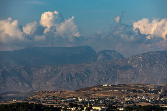 Scenic view of the Manavgat surroundings and majestic Taurus mountains under a dramatic sky with fluffy clouds in the warm glow of the evening sun in Turkey.